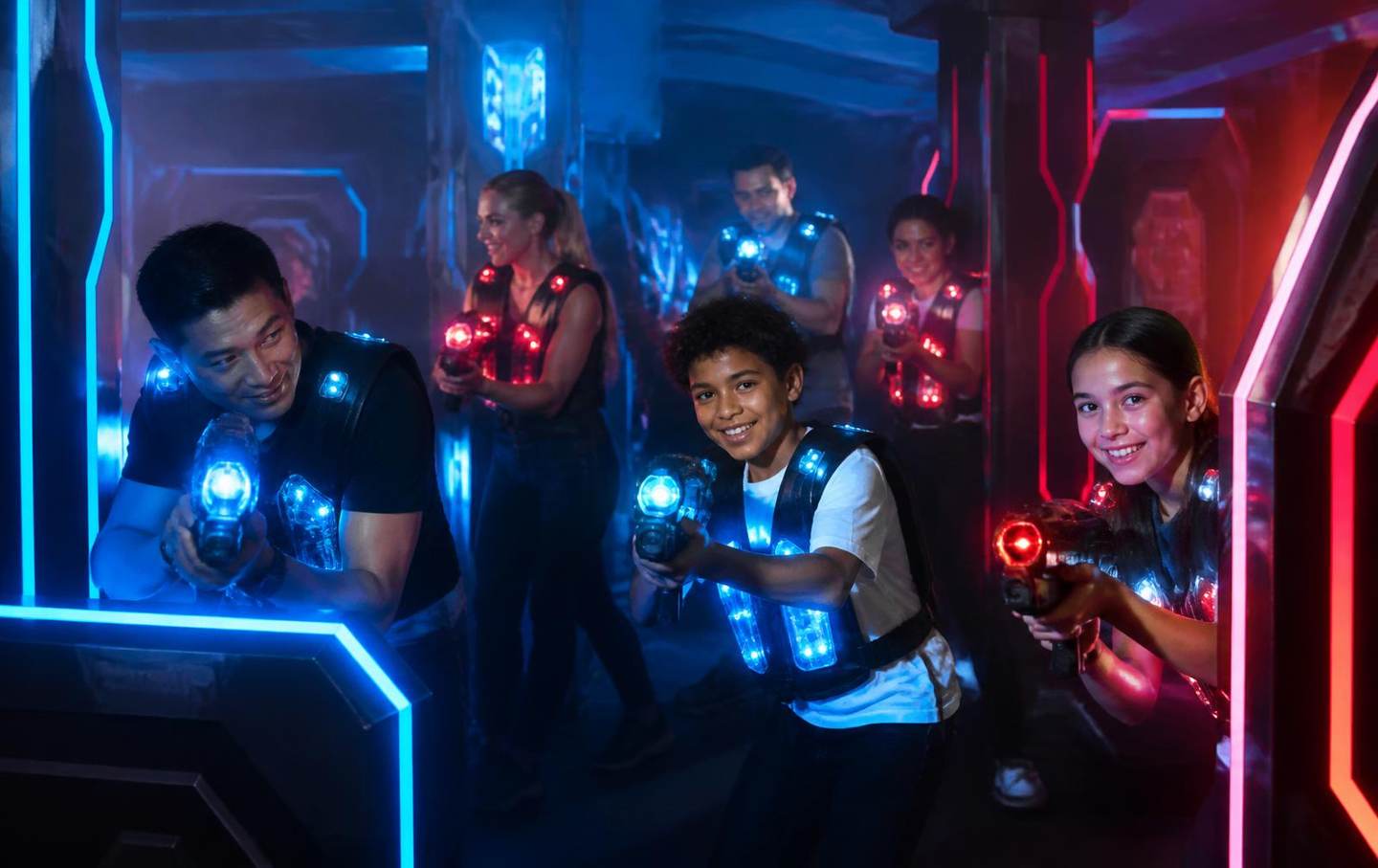Équipe de joueurs casqués de lumière bleue et rouge progressant dans une arène de laser tag brumeuse