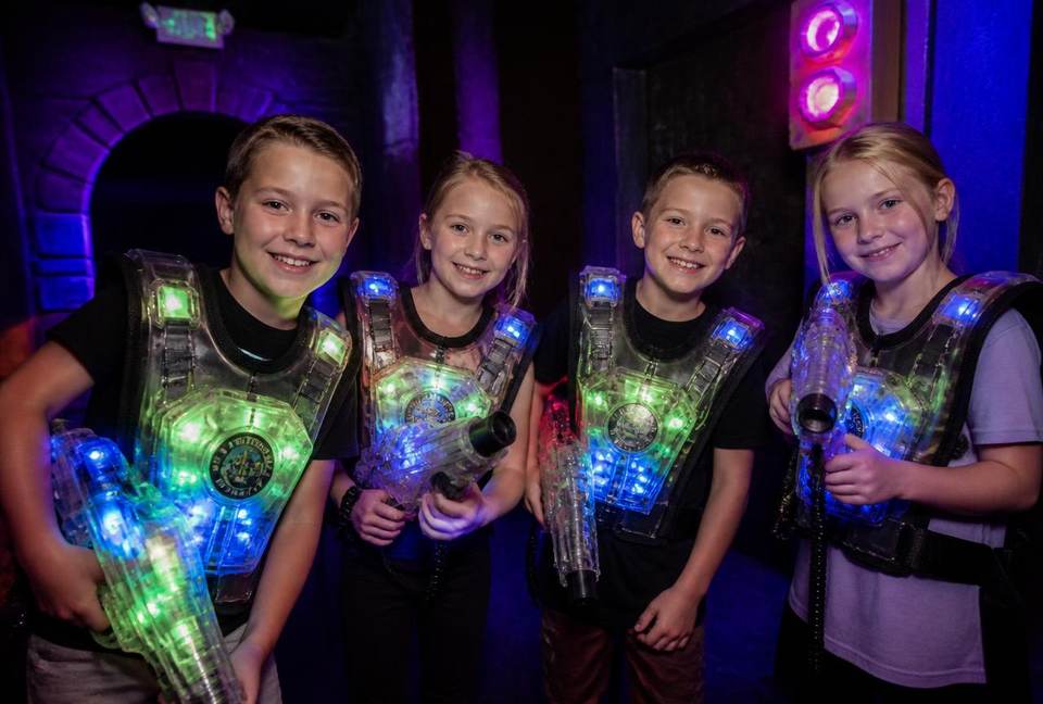 Groupe d'enfants souriants portant des gilets lumineux lors d'un anniversaire laser tag