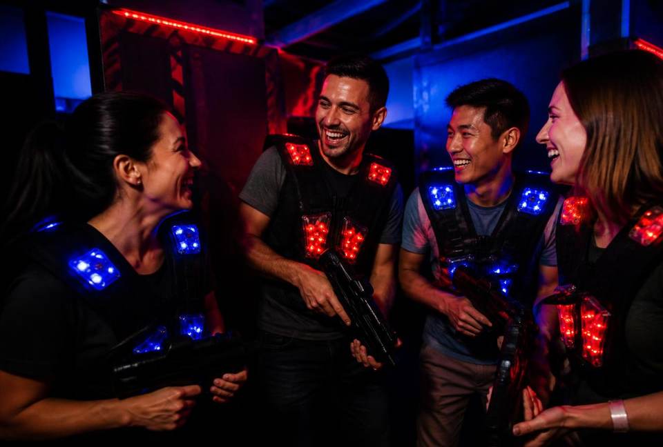 Collègues en tenue décontractée riant pendant une session de laser tag en team building
