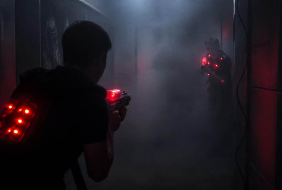 Joueurs se rapprochant dans la pénombre, gilets clignotant en rouge dans la fumée